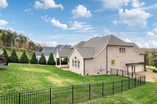 view of side of property featuring a trampoline, a yard, a patio, and a garage