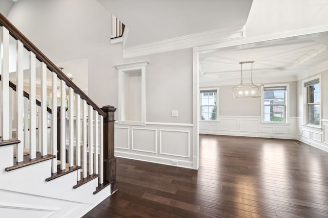 foyer with dark hardwood / wood-style flooring, ornamental molding, and a chandelier