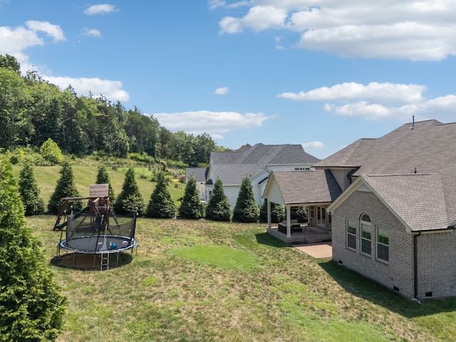 view of yard with a trampoline and a patio area