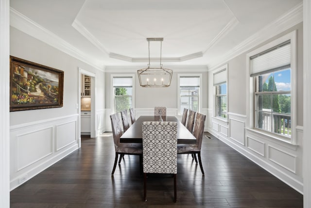 dining area featuring crown molding, dark wood-type flooring, and a tray ceiling