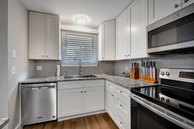 kitchen with dark wood-type flooring, white cabinets, sink, appliances with stainless steel finishes, and tasteful backsplash