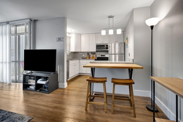 kitchen featuring white cabinetry, a healthy amount of sunlight, stainless steel appliances, and wood-type flooring