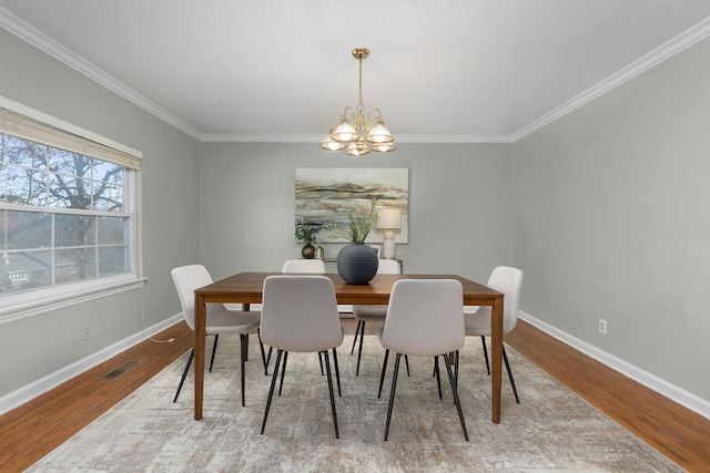 dining space with a notable chandelier, crown molding, and light hardwood / wood-style flooring