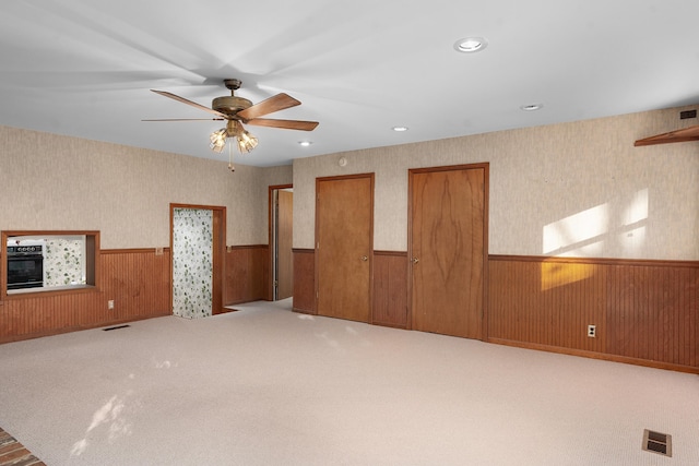 spare room with carpet flooring, ceiling fan, and wooden walls