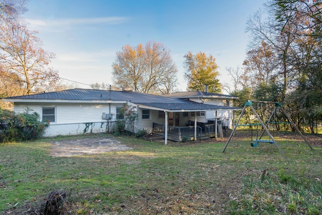 back of property featuring a playground and a lawn