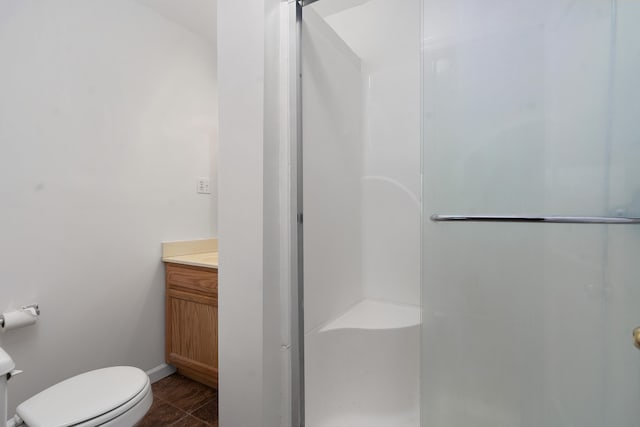 bathroom featuring tile patterned flooring, vanity, toilet, and a shower with door