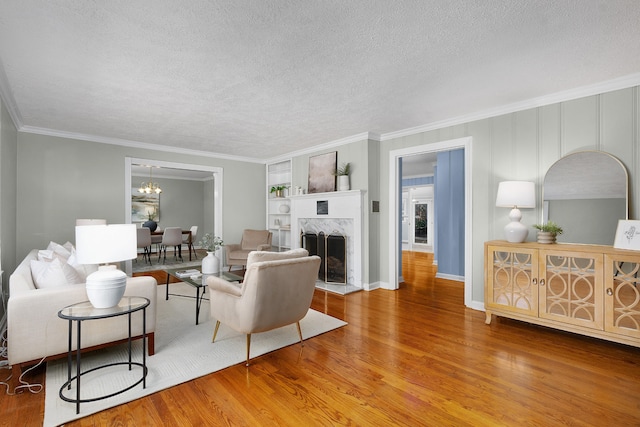 living room featuring wood-type flooring, a textured ceiling, ornamental molding, and a premium fireplace