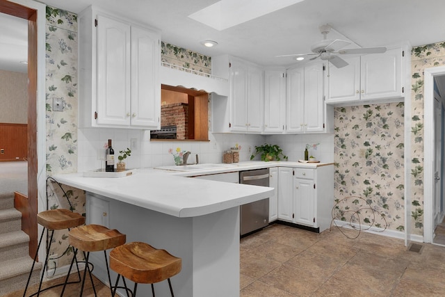 1206 Peter Pan Rd, Lookout Mountain, GA 30750 - kitchen featuring wallpapered walls, dishwasher, a skylight, a peninsula, and a breakfast bar area
