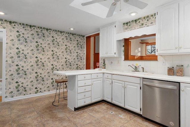 kitchen with kitchen peninsula, white cabinets, a breakfast bar, sink, and dishwasher