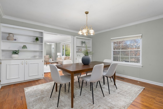 dining space with hardwood / wood-style floors, ornamental molding, and a notable chandelier