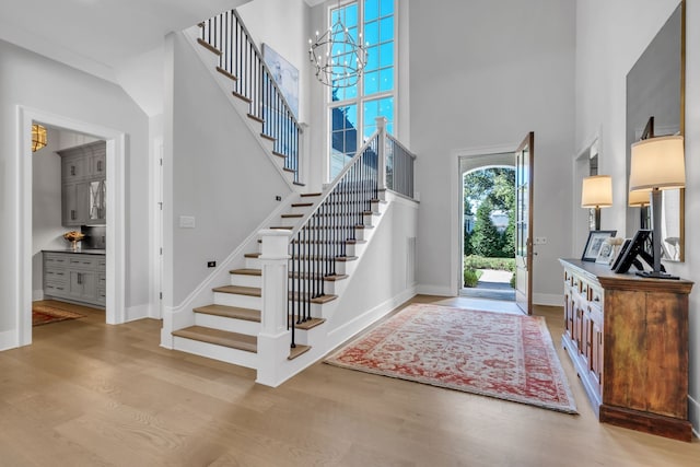 foyer entrance with light hardwood / wood-style floors, a high ceiling, and a notable chandelier