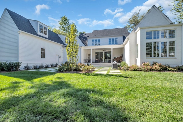 rear view of property featuring ceiling fan and a yard