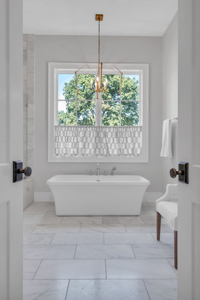 bathroom featuring a tub to relax in, plenty of natural light, and a notable chandelier