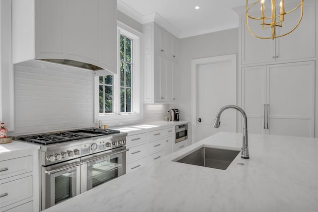 kitchen with pendant lighting, backsplash, sink, appliances with stainless steel finishes, and white cabinetry