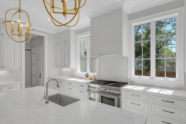 kitchen with white cabinets, backsplash, stainless steel stove, and sink