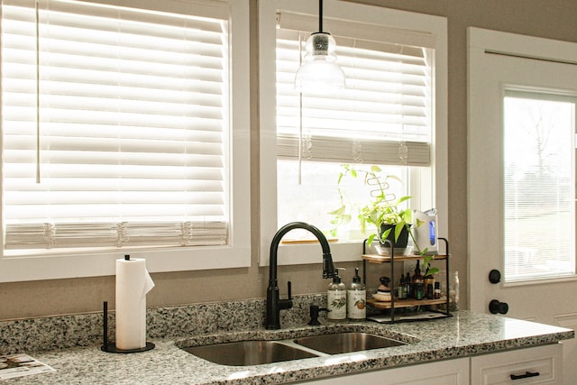 details with white cabinetry, light stone countertops, sink, and hanging light fixtures