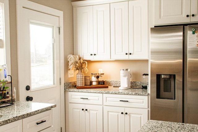 kitchen with white cabinets, stainless steel fridge, and light stone countertops