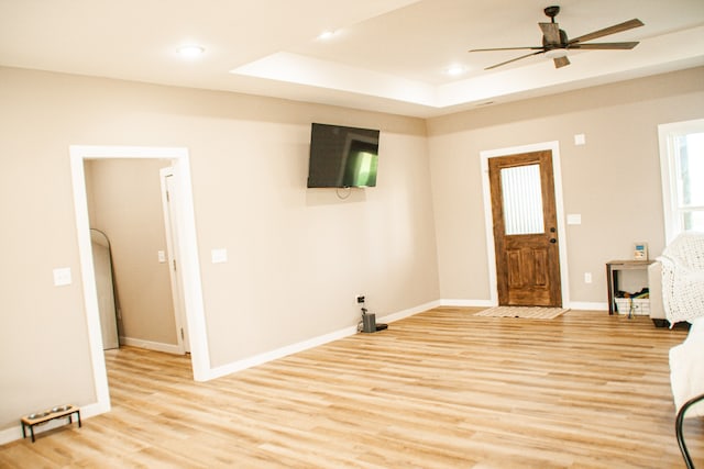 entrance foyer featuring light hardwood / wood-style floors, a raised ceiling, and ceiling fan