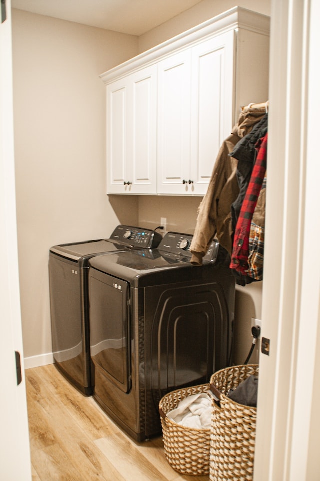 laundry area featuring cabinets, independent washer and dryer, and light hardwood / wood-style flooring