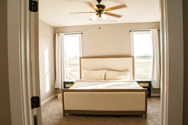 carpeted bedroom with ceiling fan and multiple windows