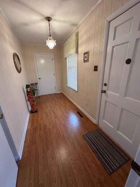 entryway featuring a chandelier, wood-type flooring, and crown molding