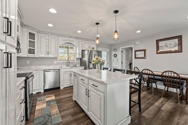 kitchen with a center island, white cabinetry, dark wood-type flooring, and appliances with stainless steel finishes