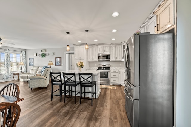 kitchen with dark hardwood / wood-style floors, a breakfast bar, stainless steel appliances, and decorative light fixtures