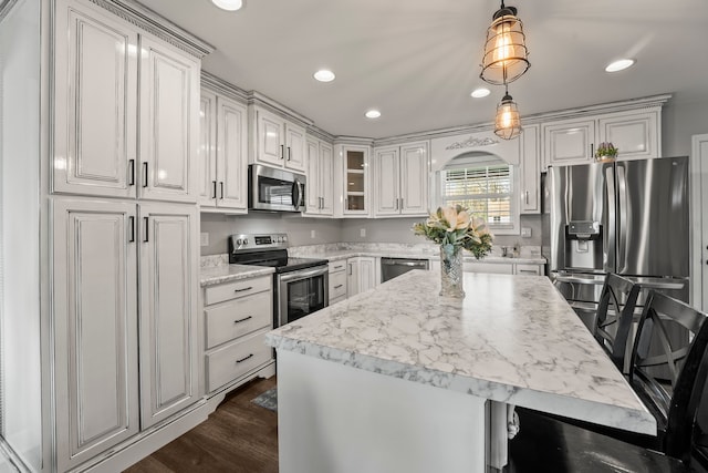 kitchen with dark wood-type flooring, white cabinets, light stone countertops, appliances with stainless steel finishes, and decorative light fixtures