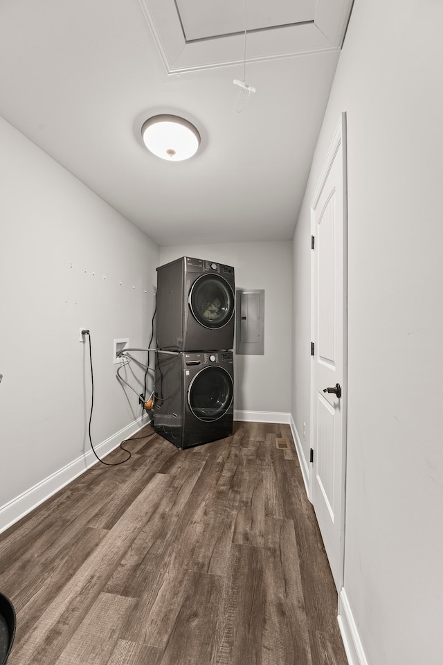 washroom featuring hardwood / wood-style flooring, stacked washer / drying machine, and electric panel