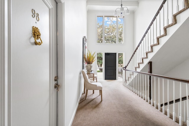 carpeted entryway with a high ceiling and an inviting chandelier