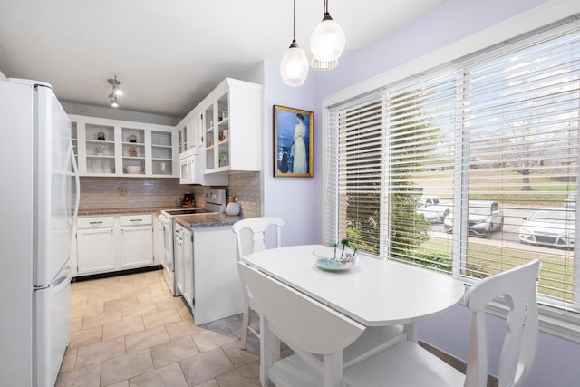 kitchen with pendant lighting, white cabinetry, white appliances, and a wealth of natural light