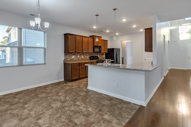 kitchen featuring tasteful backsplash, black appliances, wood-type flooring, decorative light fixtures, and an inviting chandelier