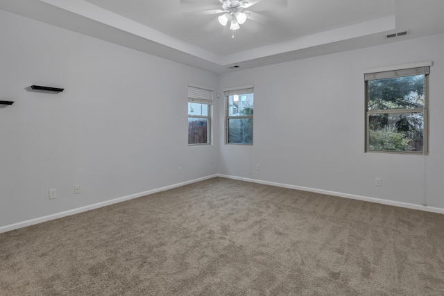 carpeted spare room featuring a tray ceiling and ceiling fan