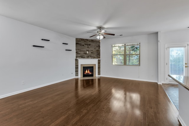 unfurnished living room featuring ceiling fan, a fireplace, and dark wood-type flooring