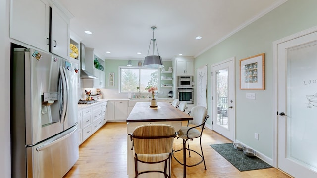 kitchen featuring appliances with stainless steel finishes, a kitchen island, light hardwood / wood-style floors, white cabinetry, and hanging light fixtures