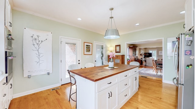 kitchen featuring a center island, hanging light fixtures, light hardwood / wood-style flooring, appliances with stainless steel finishes, and white cabinetry