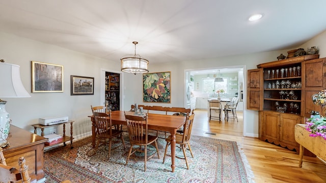 dining space with light hardwood / wood-style flooring and a notable chandelier