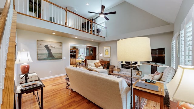 living room with light hardwood / wood-style flooring, high vaulted ceiling, and ceiling fan