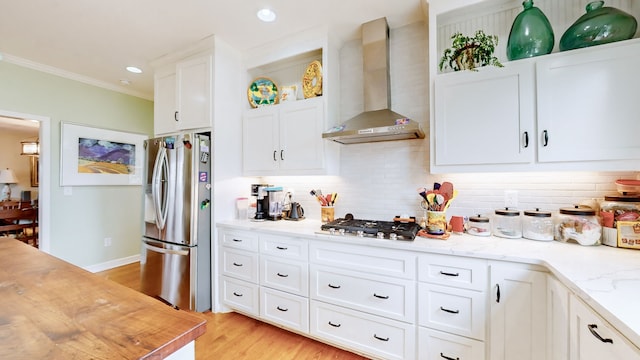 kitchen with wall chimney range hood, tasteful backsplash, light hardwood / wood-style floors, white cabinetry, and stainless steel appliances