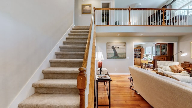 stairway featuring wood-type flooring and a towering ceiling