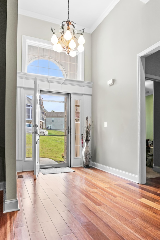 foyer entrance with hardwood / wood-style floors, a chandelier, and ornamental molding