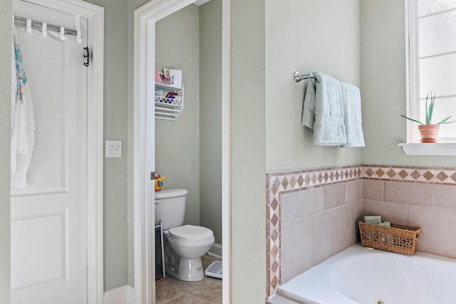 bathroom with tile patterned floors, toilet, a bathing tub, and tile walls