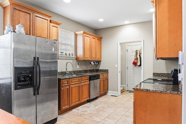 kitchen featuring dark stone countertops, light tile patterned flooring, sink, and stainless steel appliances