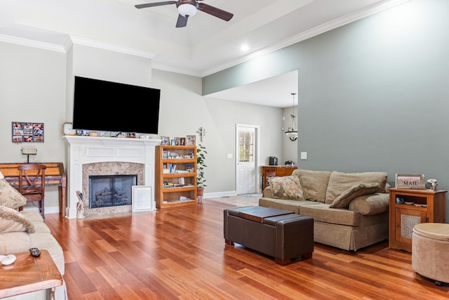 living room with hardwood / wood-style floors, ceiling fan, crown molding, and a high end fireplace