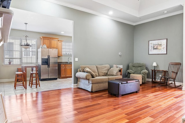 living room with crown molding, sink, and light hardwood / wood-style floors