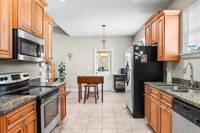 kitchen with dark stone counters, sink, light tile patterned floors, and stainless steel appliances