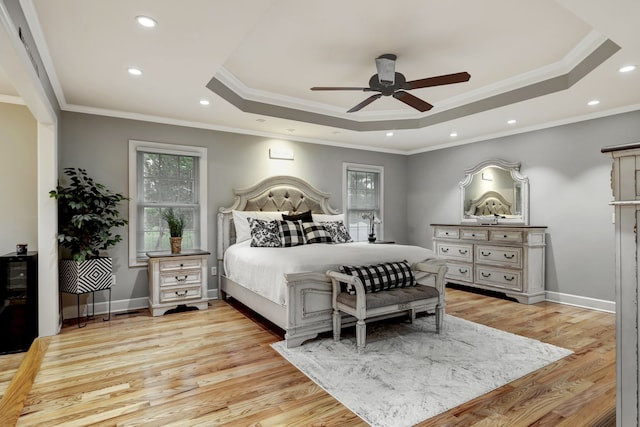 bedroom with light wood-type flooring, a raised ceiling, ceiling fan, and ornamental molding