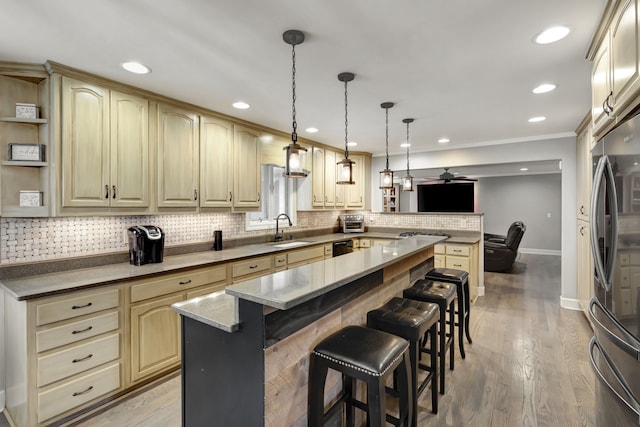 kitchen with appliances with stainless steel finishes, a kitchen breakfast bar, sink, light hardwood / wood-style flooring, and a center island