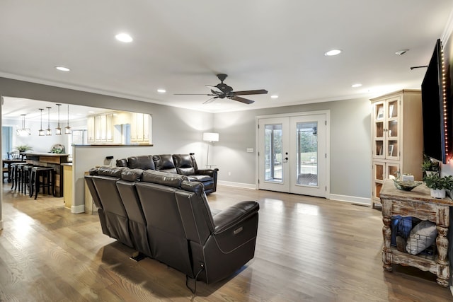 living room featuring ceiling fan, french doors, crown molding, and light wood-type flooring