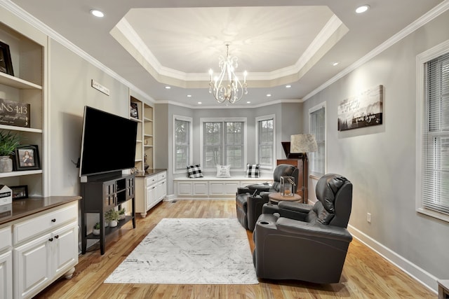 living area featuring a chandelier, a raised ceiling, crown molding, and light hardwood / wood-style floors